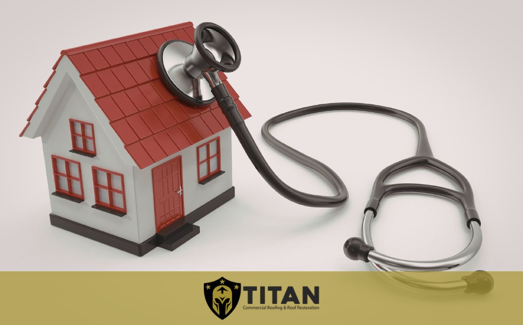 A stethoscope rests on the roof of a model house, suggesting a home checkup or inspection. The image features the Titan company logo at the bottom.